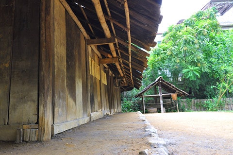 Nhà người H'Mông làm bằng gỗ nhưng lợp tranh, riêng ở huyện Mù Căng Chải, tỉnh Yên Bái lại có nét độc đáo riêng biệt là toàn bộ nhà được làm bằng gỗ pơmu. Tiến sĩ Vi Văn An đã trực tiếp tìm kiếm, đưa ngôi nhà này từ bản Đề Chờ Chua, xã Púng Luông về dựng tại Bảo tàng từ năm 1999. Mặt trước... ...và mặt sau ngôi nhà Mặt bên trái, thường là nơi để nước sinh hoạt Mặt bên phải, nhà người H'Mông thường để Cối xay ngô Theo tiến sĩ Vi Văn An, bảo tàng đã sử dụng tới khảng gần 700 tấm gỗ để lợp lại toàn bộ phần mái nhà chính, nhà nuôi gia súc, nhà lò rèn đúc lưỡi cày. Các tấm gỗ loại này phải tìm, đặt trước với người làng ở Púng Luông vì bây giờ người H'Mông đã lợp prôximăng. Nét độc đáo trong kiến trúc ngôi nhà của người H'Mông tương đối thống nhất theo một khuôn mẫu, dù to hay nhỏ đều phải có ba gian, nhà hầu như không có cửa sổ, chỉ có 2 cửa là cửa chính và cửa phụ dành cho phụ nữ. Điểm độc đáo này cho thấy sự thích ứng của người H'Mông ở vùng thời tiết lạnh Theo ông Lù Vàng Sa người dân tộc H'Mông cho biết đối với hai cây cột cái ở gian giữa và cây cái nóc, người H'Mông coi hai cây cột cái là cột chủ đạo trong nhà thể hiện sự ngay thẳng, cứng cáp, vững vàng của chủ nhà, nên cây cột phải là một cây rừng không bị sâu, thối, cụt ngọn Gian bên phải dùng để đặt giường khách... ...và bếp sưởi Gian bên trái dùng để đặt bếp nấu nướng... ...và buồng ngủ của vợ chồng gia chủ Gian giữa thường rộng hơn hai gian bên và là gian để bàn thờ tổ tiên, đồng thời cũng là nơi tiếp khách, ăn uống của gia đình. Chiếc Cối giã gạo... ...và đồ dùng đi làm nương thường được để hai bên góc của gian giữa ở cạnh cửa chính của ngôi nhà Chiếc máy dệt của người H'Mông Những đạo cụ âm nhạc của người H'Mông Trong đời sống hàng ngày, vui hay buồn, người H'Mông cũng mang khèn ra thổi. Người H'Mông thường thổi khèn khi xuống chợ, khi đi tìm người yêu và trong các lễ hội. Nhẩy Pao... ...đá Pao ...và đánh Cầu lông gà thường xuất hiện vào mồng 1 Tết của người H'Mông Nhà nuôi gia súc... ... và nhà lò rèn đúc lưỡi cày của người H'Mông Sản phẩm lưỡi cày của người H'Mông