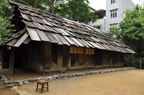 Nhà người H'Mông làm bằng gỗ nhưng lợp tranh, riêng ở huyện Mù Căng Chải, tỉnh Yên Bái lại có nét độc đáo riêng biệt là toàn bộ nhà được làm bằng gỗ pơmu. Tiến sĩ Vi Văn An đã trực tiếp tìm kiếm, đưa ngôi nhà này từ bản Đề Chờ Chua, xã Púng Luông về dựng tại Bảo tàng từ năm 1999. Mặt trước... ...và mặt sau ngôi nhà Mặt bên trái, thường là nơi để nước sinh hoạt Mặt bên phải, nhà người H'Mông thường để Cối xay ngô Theo tiến sĩ Vi Văn An, bảo tàng đã sử dụng tới khảng gần 700 tấm gỗ để lợp lại toàn bộ phần mái nhà chính, nhà nuôi gia súc, nhà lò rèn đúc lưỡi cày. Các tấm gỗ loại này phải tìm, đặt trước với người làng ở Púng Luông vì bây giờ người H'Mông đã lợp prôximăng. Nét độc đáo trong kiến trúc ngôi nhà của người H'Mông tương đối thống nhất theo một khuôn mẫu, dù to hay nhỏ đều phải có ba gian, nhà hầu như không có cửa sổ, chỉ có 2 cửa là cửa chính và cửa phụ dành cho phụ nữ. Điểm độc đáo này cho thấy sự thích ứng của người H'Mông ở vùng thời tiết lạnh Theo ông Lù Vàng Sa người dân tộc H'Mông cho biết đối với hai cây cột cái ở gian giữa và cây cái nóc, người H'Mông coi hai cây cột cái là cột chủ đạo trong nhà thể hiện sự ngay thẳng, cứng cáp, vững vàng của chủ nhà, nên cây cột phải là một cây rừng không bị sâu, thối, cụt ngọn Gian bên phải dùng để đặt giường khách... ...và bếp sưởi Gian bên trái dùng để đặt bếp nấu nướng... ...và buồng ngủ của vợ chồng gia chủ Gian giữa thường rộng hơn hai gian bên và là gian để bàn thờ tổ tiên, đồng thời cũng là nơi tiếp khách, ăn uống của gia đình. Chiếc Cối giã gạo... ...và đồ dùng đi làm nương thường được để hai bên góc của gian giữa ở cạnh cửa chính của ngôi nhà Chiếc máy dệt của người H'Mông Những đạo cụ âm nhạc của người H'Mông Trong đời sống hàng ngày, vui hay buồn, người H'Mông cũng mang khèn ra thổi. Người H'Mông thường thổi khèn khi xuống chợ, khi đi tìm người yêu và trong các lễ hội. Nhẩy Pao... ...đá Pao ...và đánh Cầu lông gà thường xuất hiện vào mồng 1 Tết của người H'Mông Nhà nuôi gia súc... ... và nhà lò rèn đúc lưỡi cày của người H'Mông Sản phẩm lưỡi cày của người H'Mông