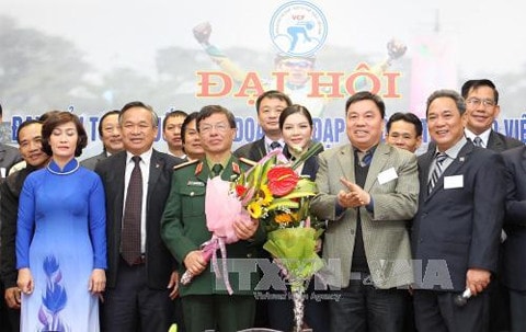 Ông Đỗ Quý Doãn, Chủ tịch Liên đoàn Xe đạp - Mô tô thể thao Việt Nam khóa V (thứ hai từ phải sang) tặng hoa chúc mừng tân Chủ tịch khóa VI Phạm Văn Huấn. Ảnh: TTXVN