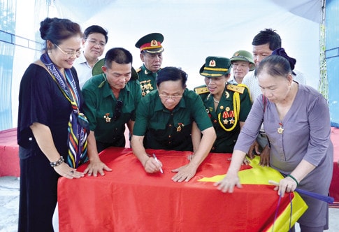Những thành viên trong đoàn ký tên lên lá cờ Tổ quốc kỷ niệm chuyến hành trình ý nghĩa tại Thành phố Vinh, Nghệ An