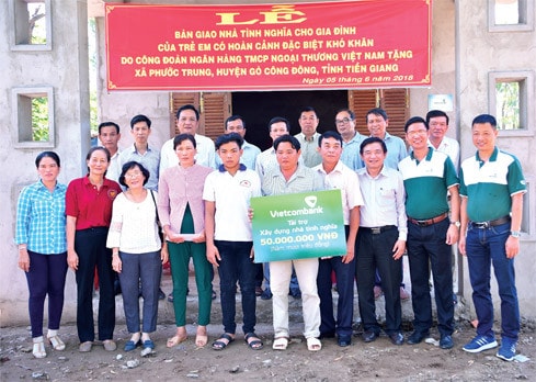 Gia đình ông Huỳnh Văn Được cùng đại diện Vietcombank và lãnh đạo địa phương chụp ảnh lưu niệm bên ngôi nhà mới