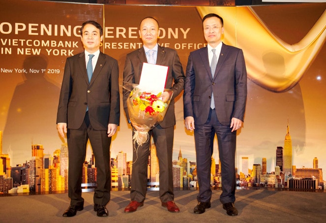 Ông Nghiêm Xuân Thành - Chủ tịch HĐQT (bên trái) và ông Phạm Quang Dũng – Tổng Giám đốc (bên phải) trao quyết định và tặng hoa chúc mừng ông Trần Việt Anh- Phó Giám đốc Công ty TNHH Chứng khoán Vietcombank được điều động và bổ nhiệm Trưởng VPĐD Vietcombank tại Mỹ