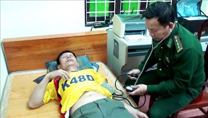 Lực lượng quân y Đồn Biên phòng Roòn, Bộ Chỉ huy Bộ đội Biên phòng tỉnh Quảng Bình sơ cứu, chăm sóc sức khỏe cho thuyền viên tàu Thành Công 999 bị nạn. (Ảnh: Võ Dung/TTXVN)