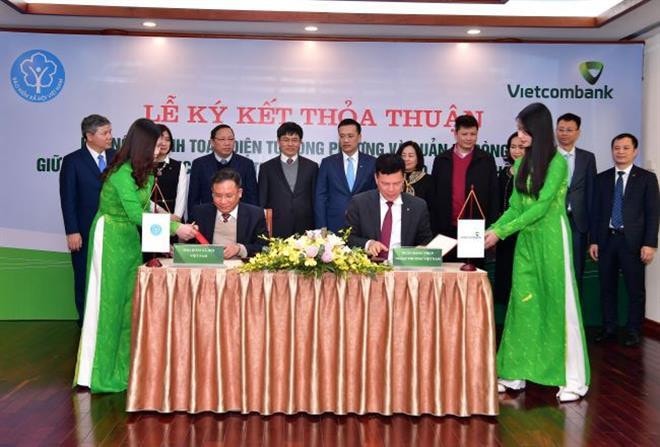 Phó Tổng Giám đốc Vietcombank Phạm Mạnh Thắng (ngồi bên phải) và Phó Tổng Giám đốc BHXH Việt Nam Lê Hùng Sơn (ngồi bên trái) ký kết Thỏa thuận