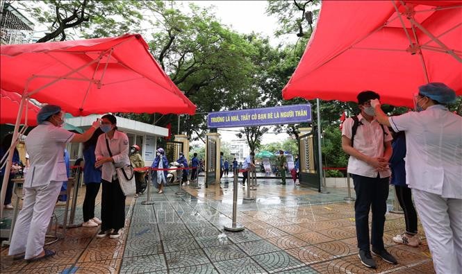 Đo thân nhiệt, sát khuẩn tay cho thí sinh trước khi vào phòng thi tại điểm thi trường THPT Trần Nhân Tông - Ảnh: TTXVN
