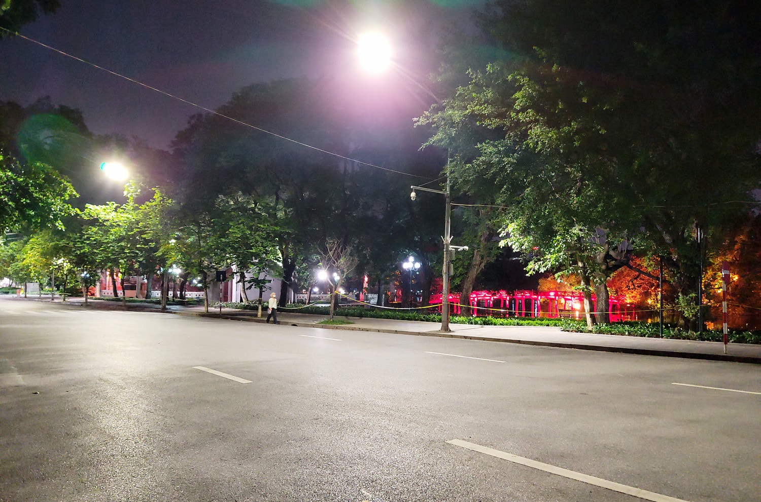 Một người đang lặng lẽ bước đi trước khu vực Đền Ngọc Sơn