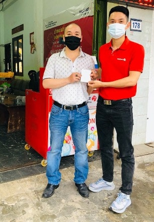 Đại diện Vietlott (áo đỏ) nhận tấm vé trúng thưởng từ anh N.D.T (áo trắng)