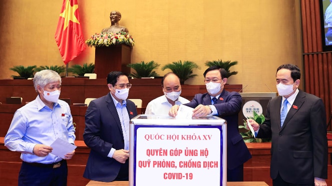 Các đồng chí Ủy viên Bộ Chính trị: Chủ tịch Nước Nguyễn Xuân Phúc, Thủ tướng Chính phủ Phạm Minh Chính, Chủ tịch Quốc hội Vương Đình Huệ và các đại biểu Quốc hội quyên góp ủng hộ Quỹ vaccine phòng, chống dịch COVID-19. (Ảnh: TTXVN)