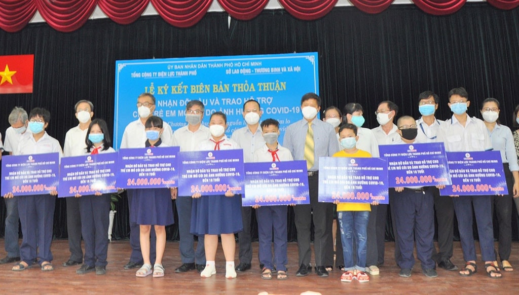 Chủ tịch Công đoàn EVNHCMC (mang cravat) cùng đại diện Sở Lao động, Thương binh và Xã hội TP. Hồ Chí Minh trao biểu trưng bảo trợ cho các em bị ảnh hưởng nặng nề bởi dịch Covid-19