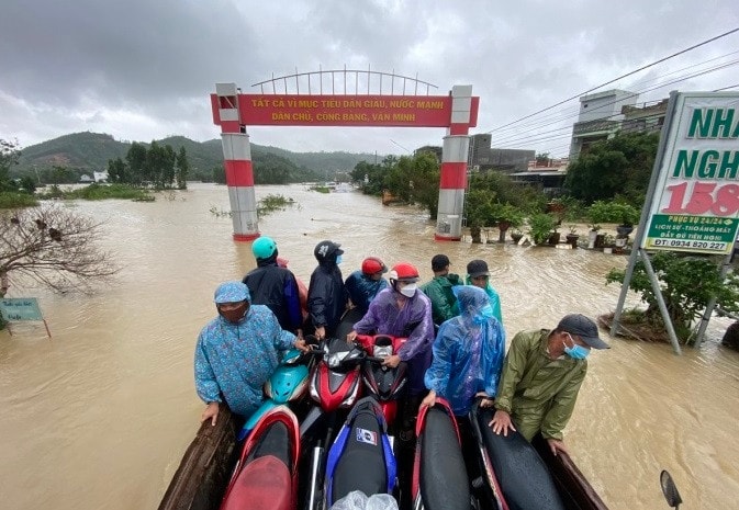 Người dân Tuy Phước thuê xe cơ giới chở xe máy qua vùng ngập nước, sáng 30/11