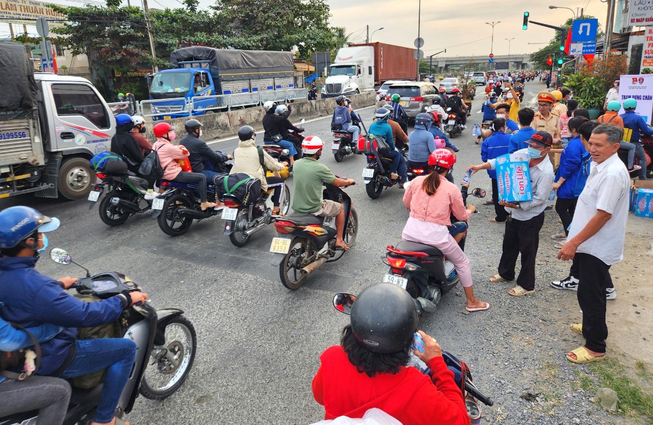 Dòng người đổ về quê ăn Tết được tặng nước suối, khăn lạnh. Đang về quê đón Tết, bất ngờ được CSGT phát mũ bảo hiểm, nước uống, khăn lạnh