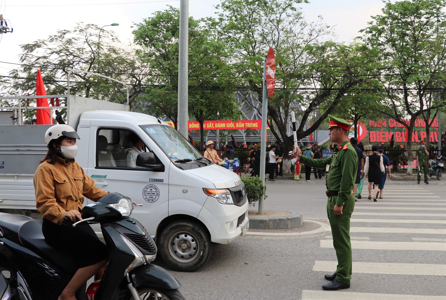 Cán bộ Công an TP. Điện Biên Phủ dừng phương tiện để du khách di chuyển từ di tích Nghĩa trang A1 sang Bảo tàng Chiến thắng lịch sử Điện Biên Phủ an toàn