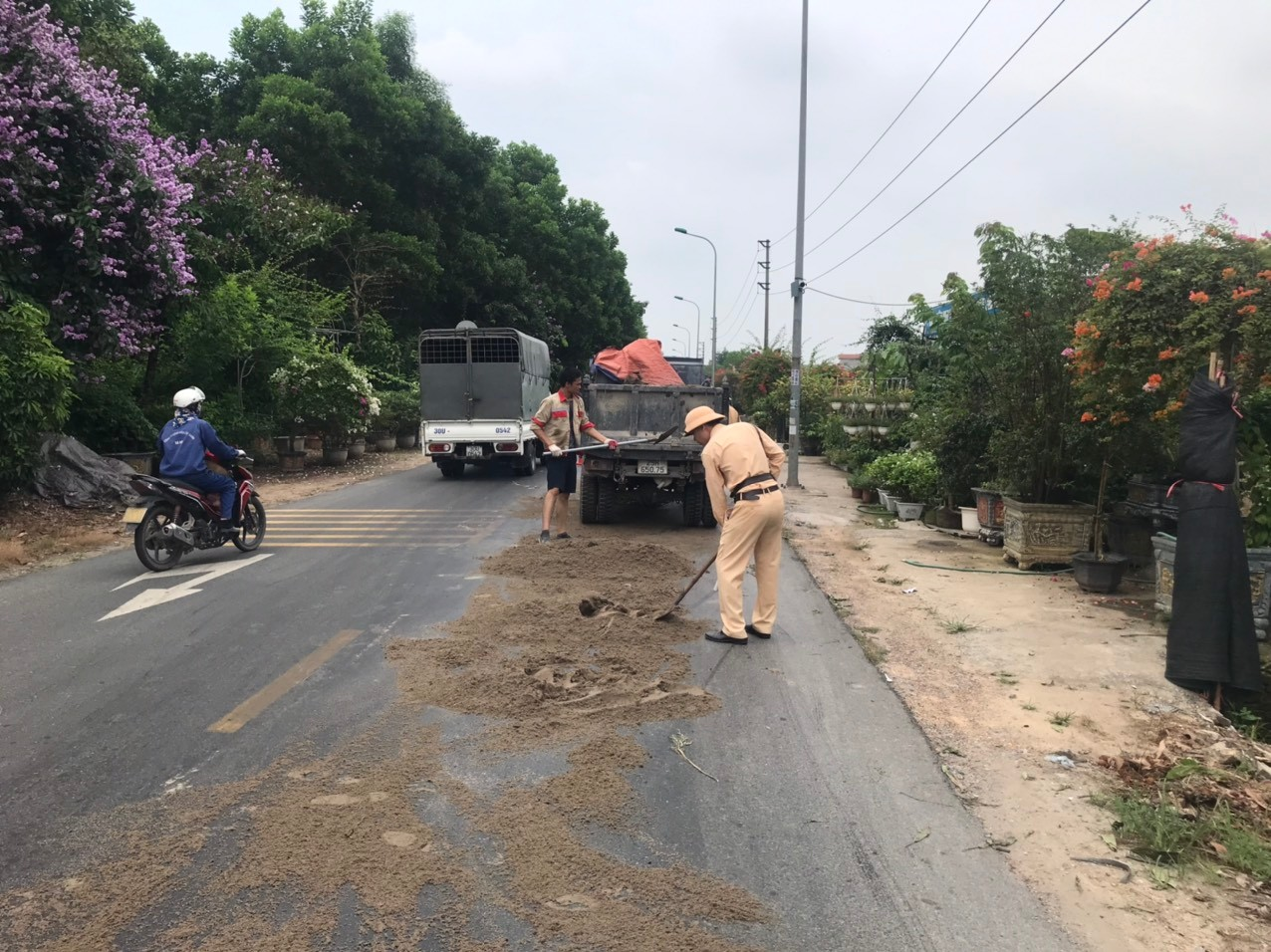 Cán bộ Đội Cảnh sát giao thông đường bộ số 15 cùng nhân dân rải cát khắc phục vệ dầu trên đường gom Võ Nguyên Giáp sáng 29.5