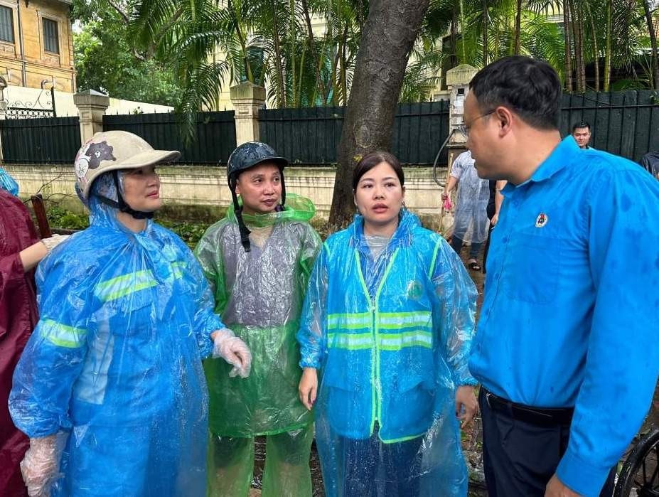 Chủ tịch Liên đoàn lao động thành phố Hà Nội Phạm Quang Thanh động viên công nhân Công ty Trách nhiệm hữu hạn một thành viên Môi trường đô thị Hà Nội đang thu gom cành, lá cây trên phố Phan Đình Phùng. Ảnh: Việt Lâm