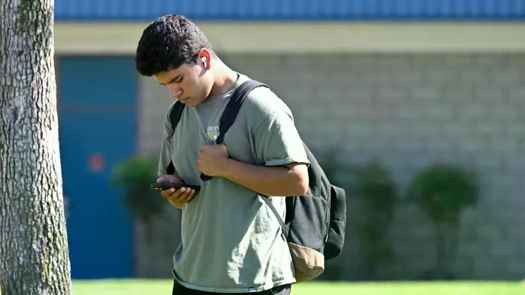 A Chino Hills High School student studies his phone intently while on campus in August. (SCNG) OCR-L-SCHOOLPHONES-0906-01.webp