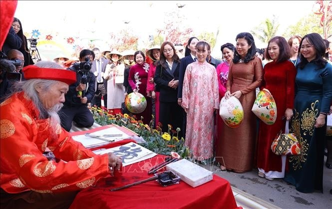 Bà Ngô Phương Ly, Phu nhân Tổng Bí thư Tô Lâm và các đại biểu xem ông đồ viết chữ. Ảnh: Văn Điệp/TTXVN