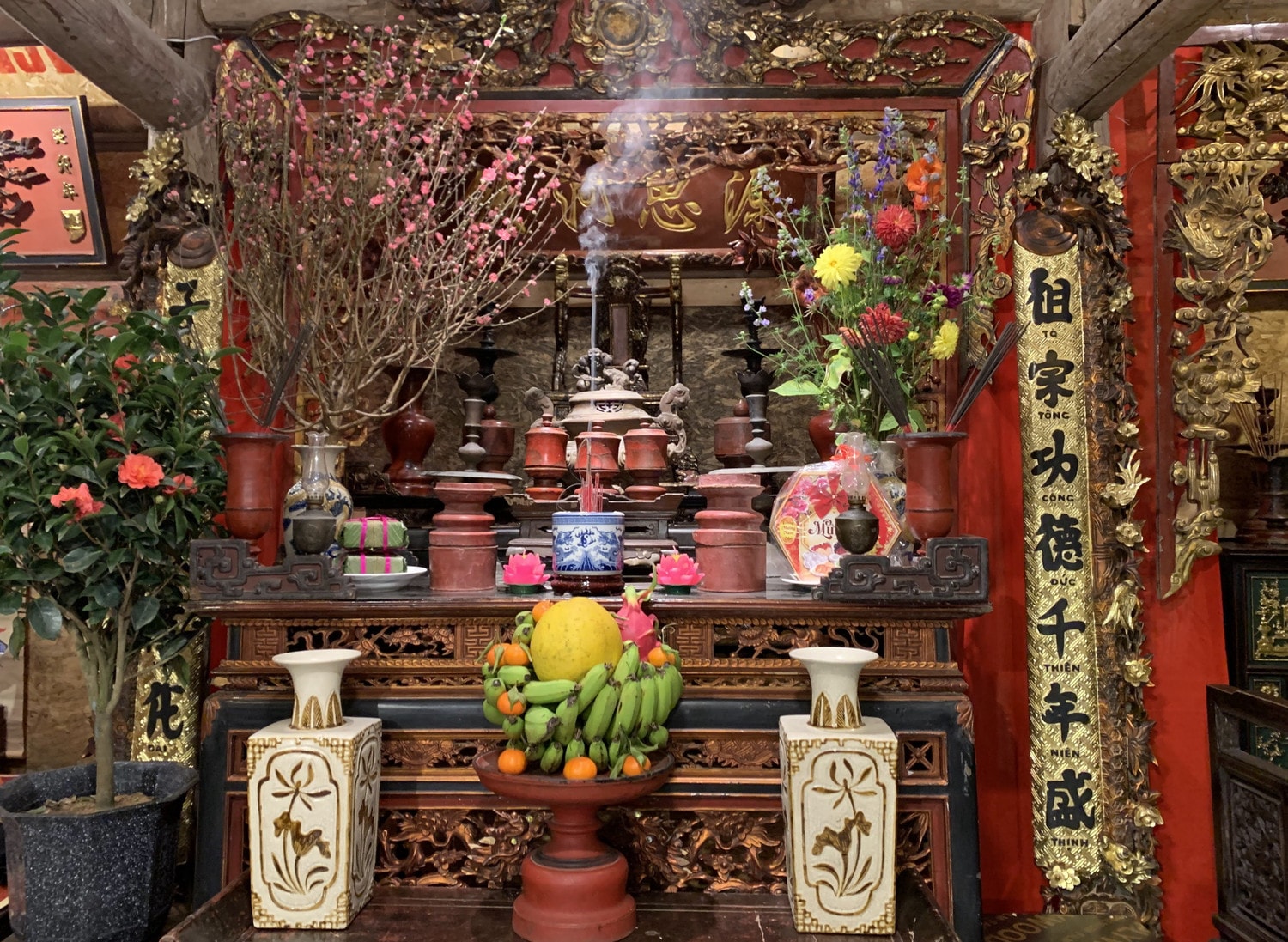 Ban thờ ấm cúng với hương thơm của nhang trầm, sắc đỏ của cánh đào nở rộ