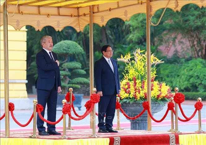 Thủ tướng Phạm Minh Chính và Thủ tướng Kyrgyzstan Adylbek Kasimalyev nghe cử hành Quốc thiều hai nước. Ảnh: Dương Giang/TTXVN