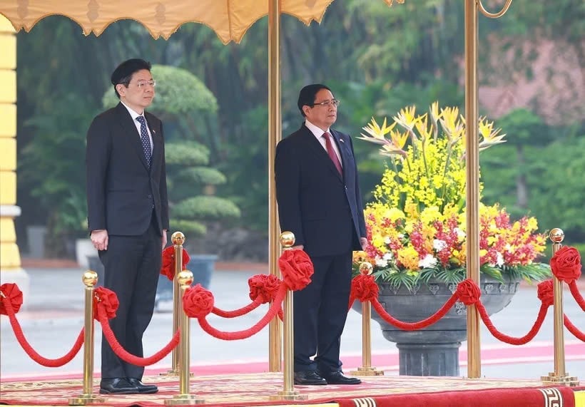 Prime Minister Pham Minh Chinh (R) and his Singaporean counterpart Lawrence Wong stand for the national anthems of Vietnam and Singapore. (Photo: VNA) z6443889583139-de3fc57809b9a2553d644c4655cea2e6.jpg