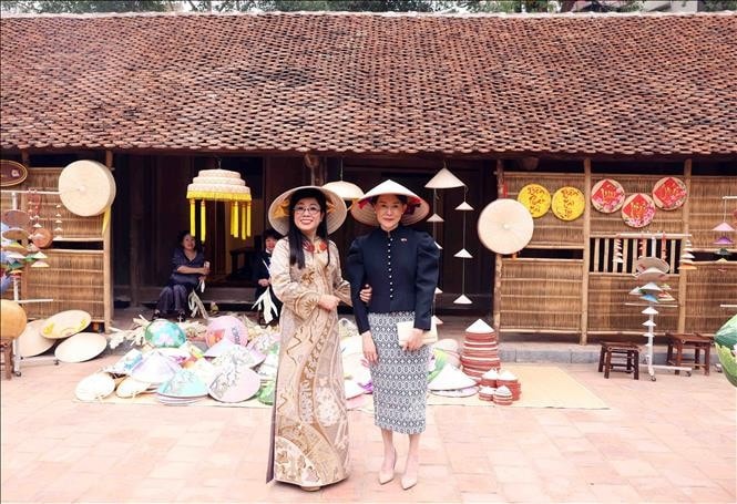 Bà Lê Thị Bích Trân, Phu nhân Thủ tướng Phạm Minh Chính cùng bà Loo Tze Lui, Phu nhân Thủ tướng Cộng hòa Singapore Lawrence Wong đội nón lá chụp ảnh lưu niệm tại Bảo tàng Dân tộc học Việt Nam. Ảnh: Phạm Kiên/TTXVN