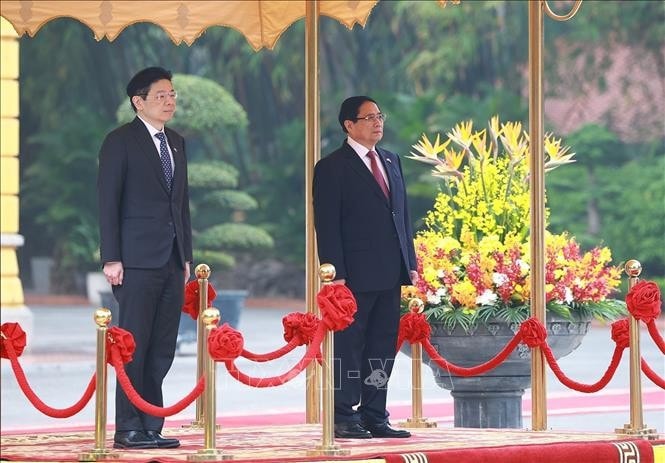 Thủ tướng Phạm Minh Chính và Thủ tướng Singapore Lawrence Wong nghe quân nhạc cử Quốc thiều hai nước. Ảnh: Dương Giang/TTXVN