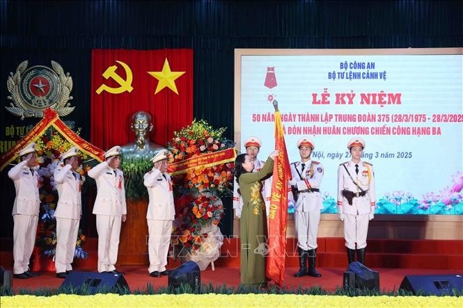 Phó Chủ tịch nước Võ Thị Ánh Xuân gắn Huân chương Chiến công hạng Ba lên lá cờ truyền thống của Trung đoàn 375, Bộ Tư lệnh Cảnh vệ - Bộ Công an. Ảnh: Phạm Kiên/TTXVN