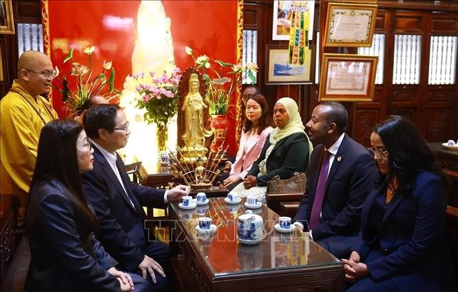 Thủ tướng Phạm Minh Chính và Phu nhân cùng Thủ tướng Ethiopia Abiy Ahmed Ali và Phu nhân nghe giới thiệu về văn hoá, lịch sử, kiến trúc chùa Trấn Quốc. Ảnh: Dương Giang/TTXVN