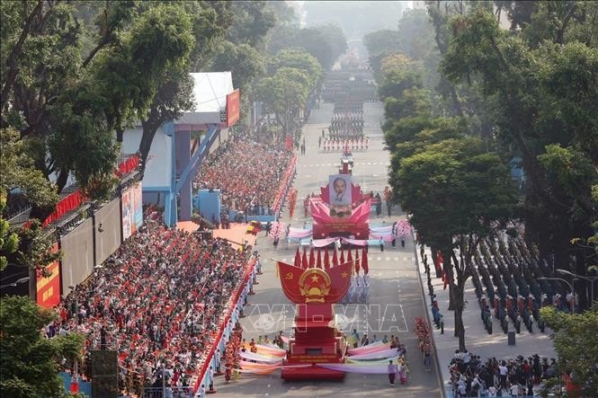 Đội hình xe mô hình Quốc huy nước Cộng hòa Xã hội Chủ nghĩa Việt Nam và Xe rước chân dung Chủ tịch Hồ Chí Minh tiến qua lễ đài. Ảnh: TTXVN