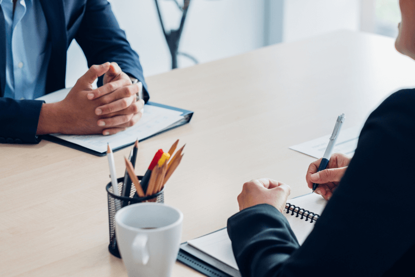 Job candidate sitting on the left being interviewed by a professional on the right.