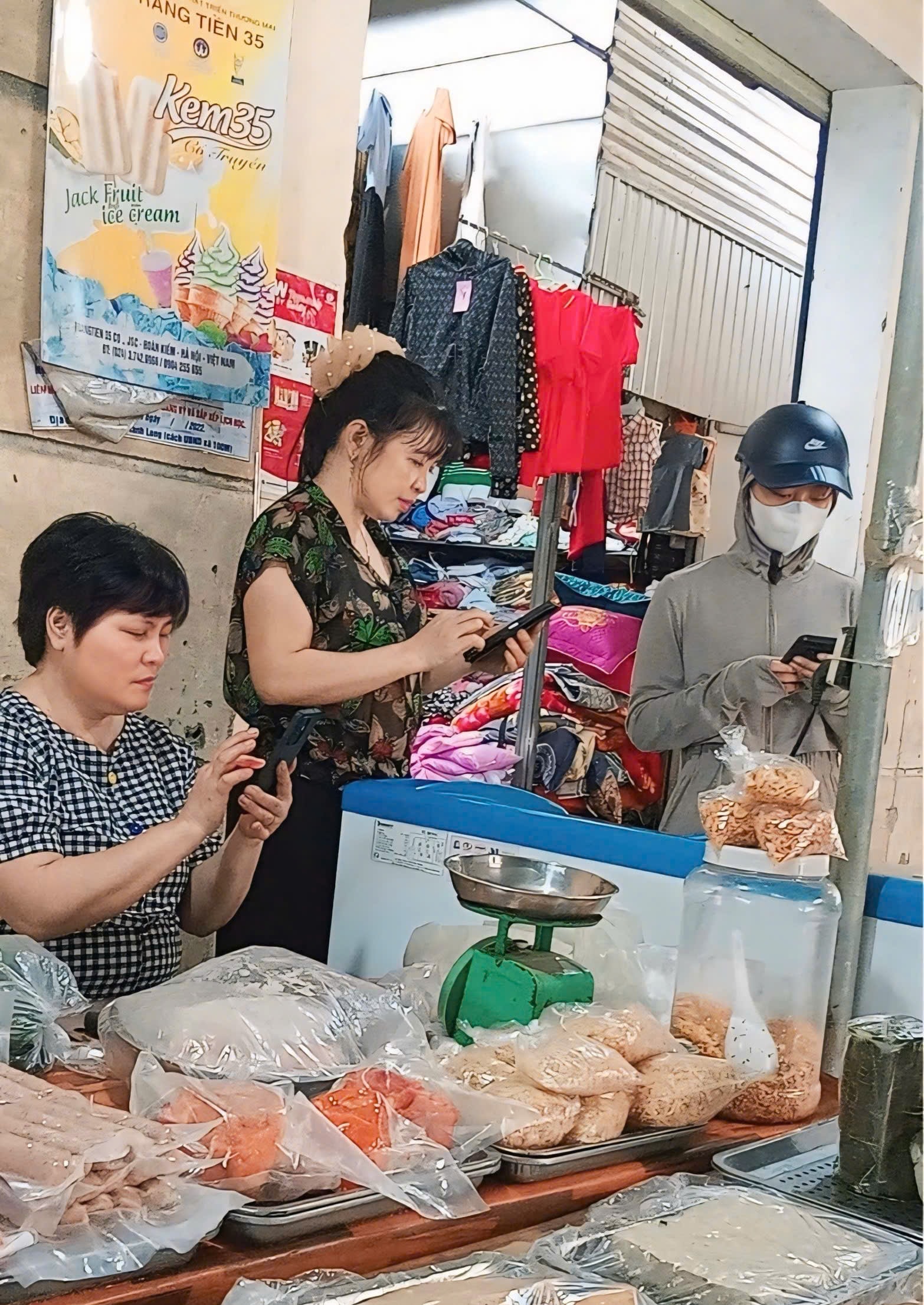 Các tiểu thương buôn bán nhỏ ở chợ Phuống (Thanh Chương, Nghệ An) theo dõi phiên thảo luận qua màn hình điện thoại. Ảnh: Hải Phong