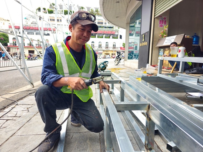 A worker installs a barrier outside the vna-potal-ha-noi-bat-dau-thao-do-di-chuyen-cac-trang-thiet-bi-va-ha-giai-cong-trinh-toa-nha-ham-ca-map-8053546.jpg