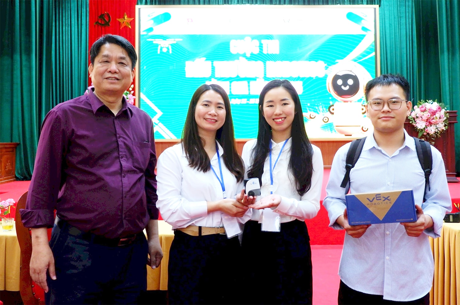 Kỹ sư Đỗ Hoàng Sơn - Liên minh STEM (bìa trái) tặng Trưởng Phòng Giáo dục và Đào tạo Bình Gia Hà Thị Thùy Dương (thứ hai, trái sang) robot VEX AIM tích hợp chức năng làm quen với trí tuệ nhân tạo