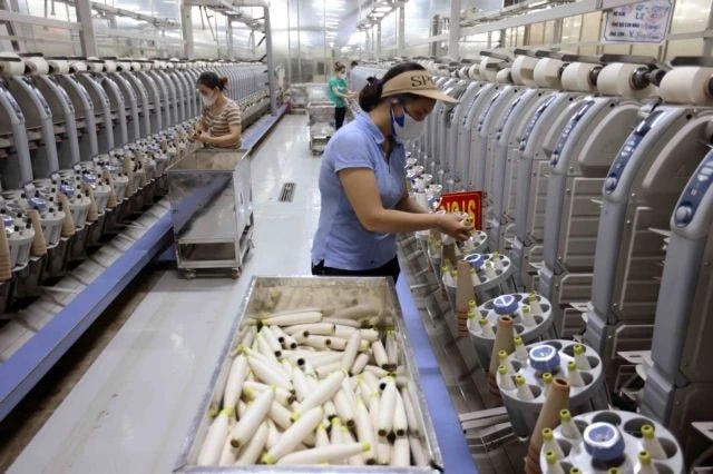Workers at a yarn production line. (Photo: VNA/VNS)