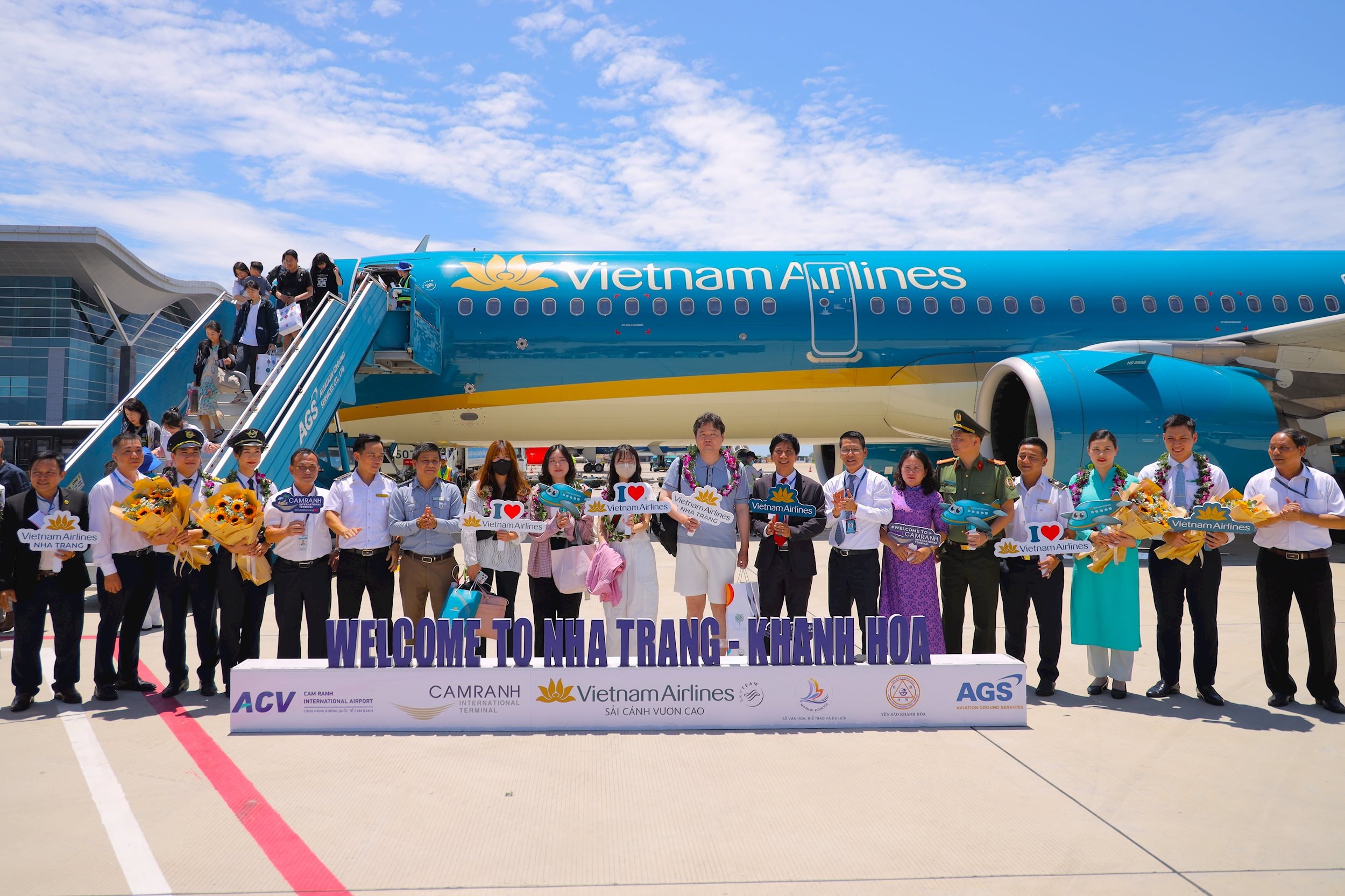 Ảnh 2 . Các đại biểu và đại diện Vietnam Airlines tặng hoa, quà lưu niệm cho hành khách và tổ bay trên chuyến bay đầu tiên từ Busan đến Nha Trang tại Cảng Hàng không quốc tế Cam Ranh. Ảnh VNA (1)