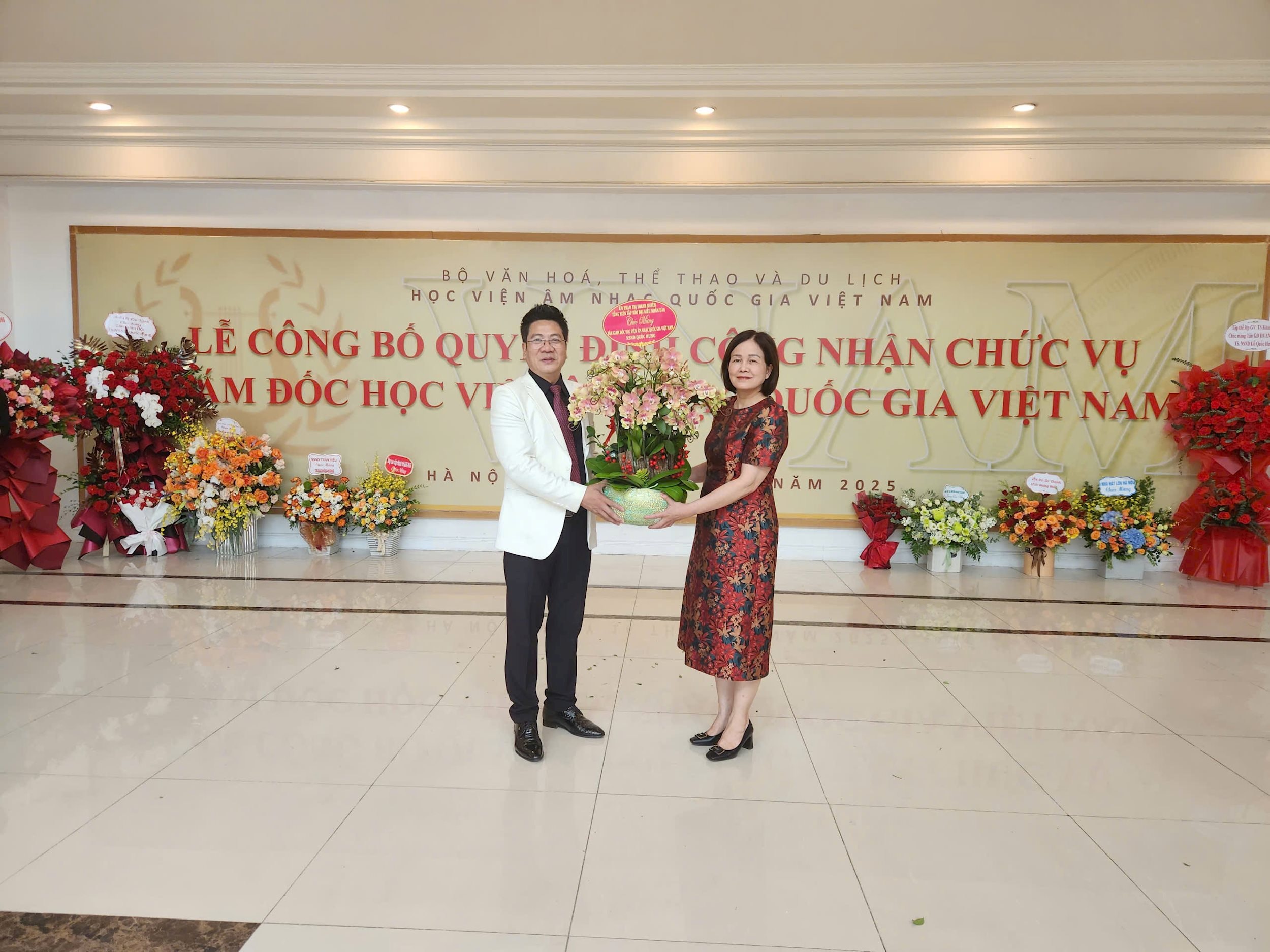 Phó Tổng biên tập Nguyễn Thị Minh Hằng thay mặt Tổng biên tập Phạm Thị Thanh Huyền tặng hoa chúc mừng tân Giám đốc Học viện âmnhạc Quốc gia Việt Nam Quốc Hưng