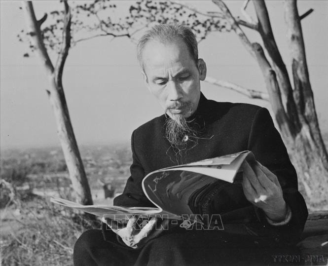 Chủ tịch Hồ Chí Minh đọc báo trước ngôi nhà nghỉ của Người khi sang thăm Trung Quốc, năm 1953. Ảnh: TTXVN
