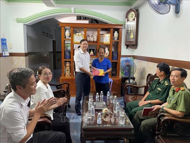 Ngo Thanh Phuc (L), Chairman of the Long Hai People’s Committee, presents a national flag to a local ship owner. (Photo: VNA)
