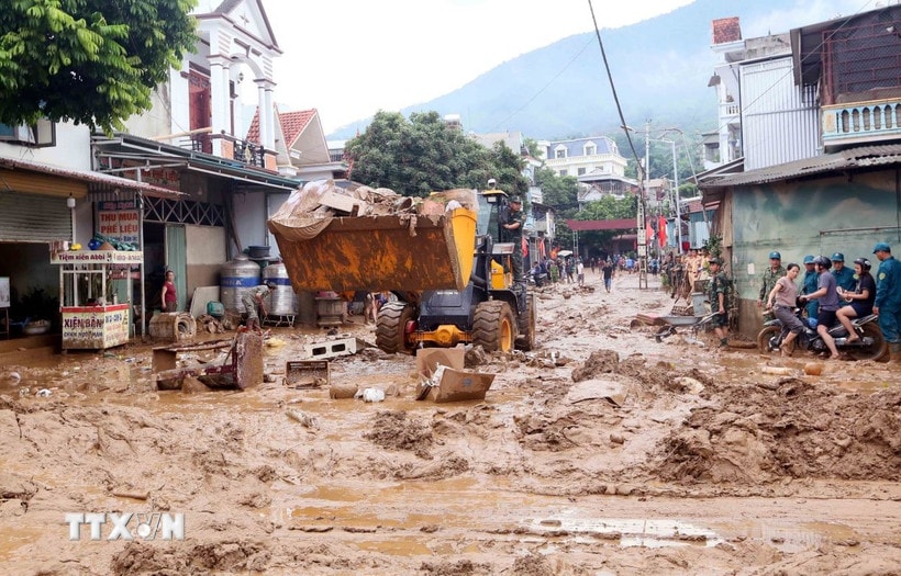 Máy xúc được huy động để hỗ trợ san gạt, thu gom bùn đất, cành cây, rác bị tràn về trong đợt lũ vừa qua tại xã Sông Mã. (Ảnh: Quang Quyết/TTXVN)