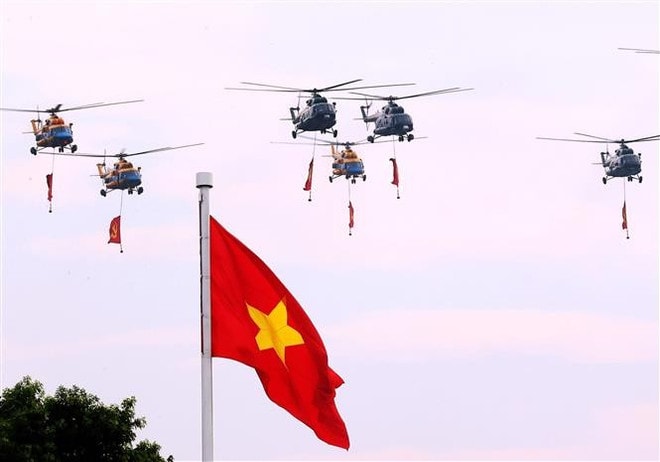 Kicking off the parade, a formation of helicopters of the Vietnam People’s Air Force carries the Party flag and the national flag over Ba Dinh Square. (Photo: VNA) helicopter-vna-national-day-parade.jpg