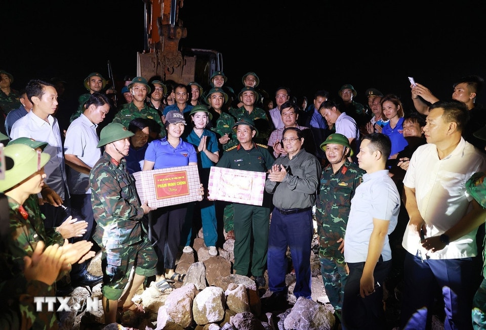 Thủ tướng Phạm Minh Chính tặng quà động viên cho các lực lượng đang gia cố đê điều, khắc phục hậu quả tại khu vực đê biển Hải Thịnh 3. (Ảnh: Dương Giang/TTXVN)