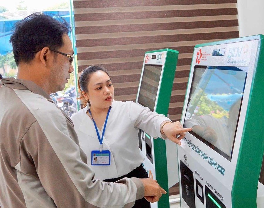 Hỗ trợ người dân thực hiện các bước tại ki-ốt thủ tục hành chính thông minh tại Trung tâm Phục vụ hành chính công tỉnh. Ảnh Nguyễn Muội