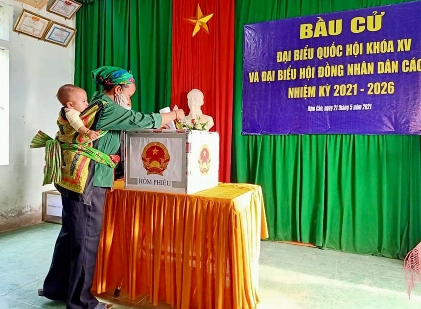 Một cử tri ở xã Nậm Càn (huyện Kỳ Sơn cũ) địu con đi bỏ phiếu.