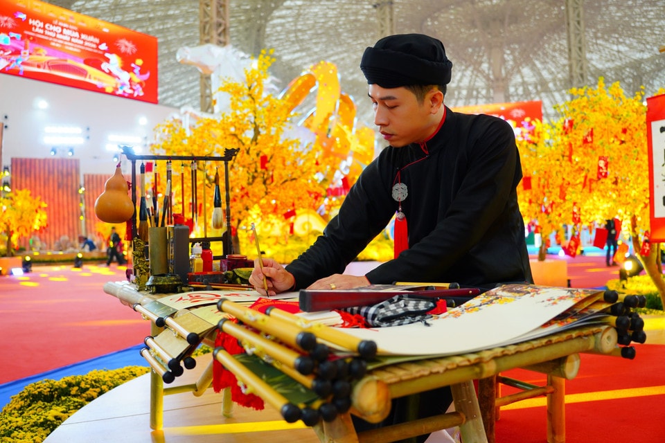 An artisan in traditional Vietnamese attire performs calligraphy. (Photo: VNA)