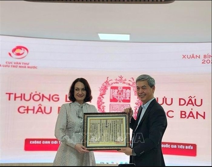 Director of the State Records and Archives Department of Vietnam Dang Thanh Tung presents Elena Bezdetko, spouse of the Russian Ambassador to Vietnam, with a woodblock print of Vietnam’s national title (Photo: VNA)