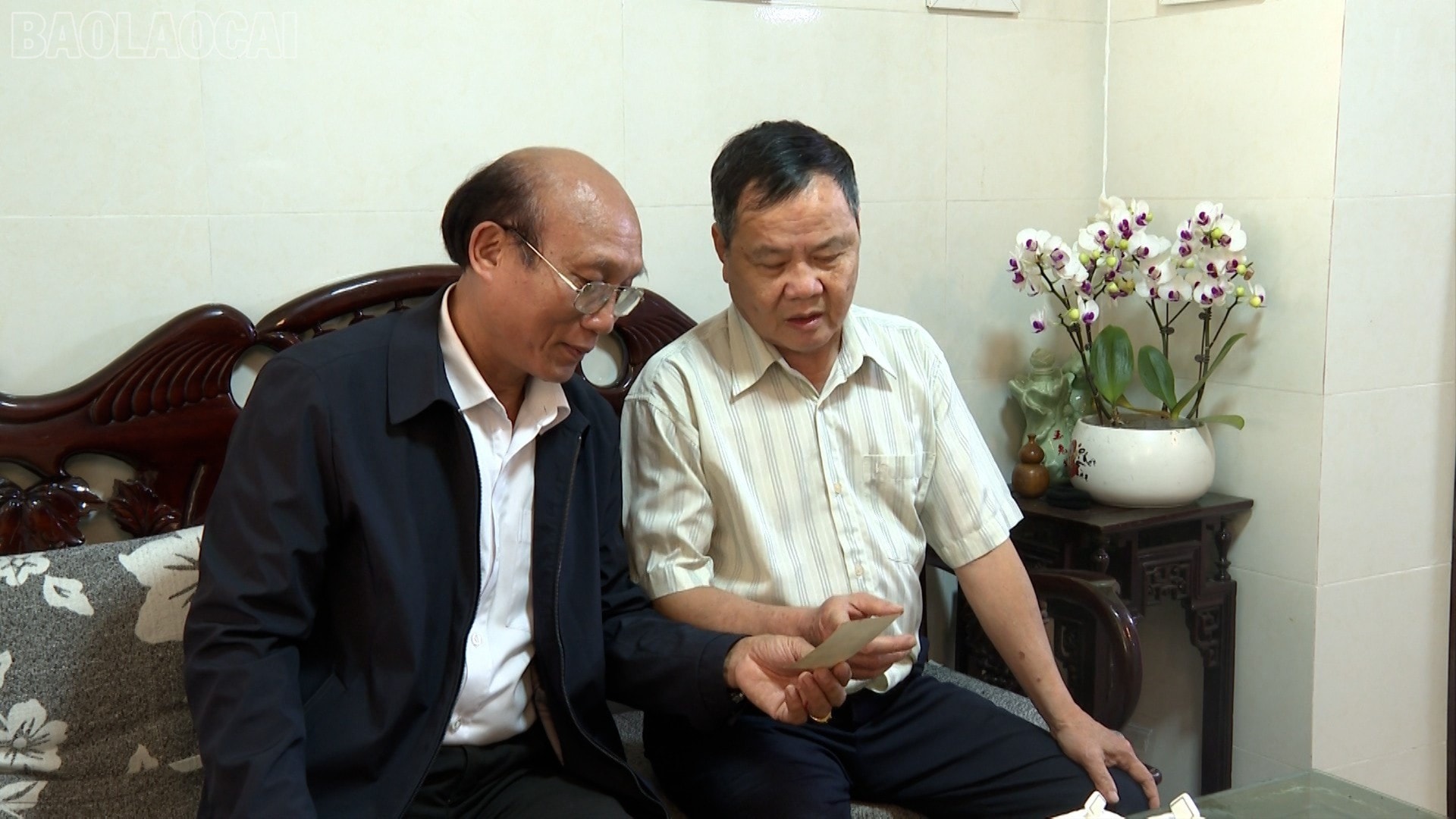 ông Nguyễn Văn Thực - tổ dân phố Nguyễn Thái Học 1, phường Yên Bái (bên phải) xem lại tấm ảnh thời còn trẻ và xúc động chia sẻ về cuộc Tổng tuyển cử bầu ra Quốc hội thống nhất, Quốc hội khóa VI