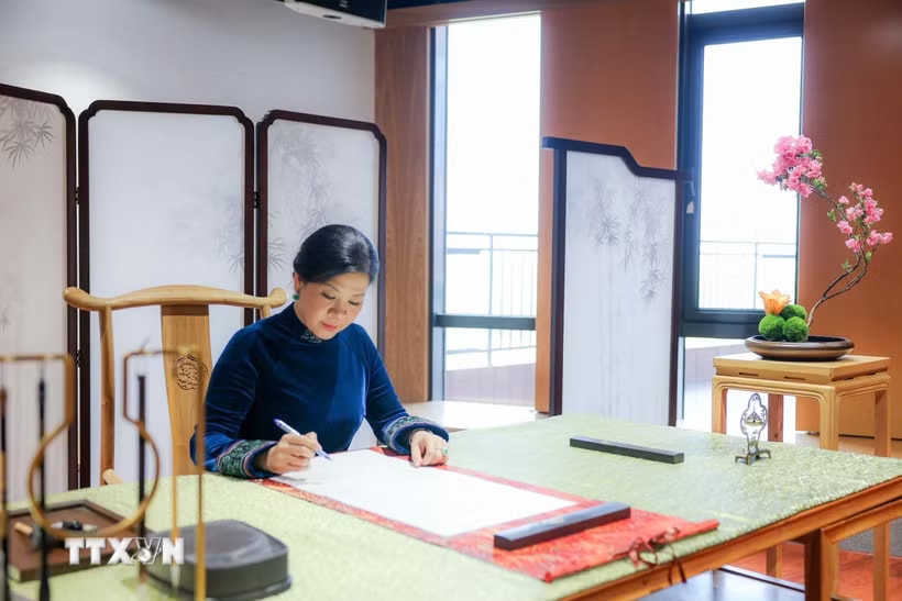 Phu nhân Ngô Phương Ly viết lưu bút tại Trung tâm giao lưu khoa học văn hóa thanh thiếu niên Tống Khánh Linh. (Ảnh: TTXVN)