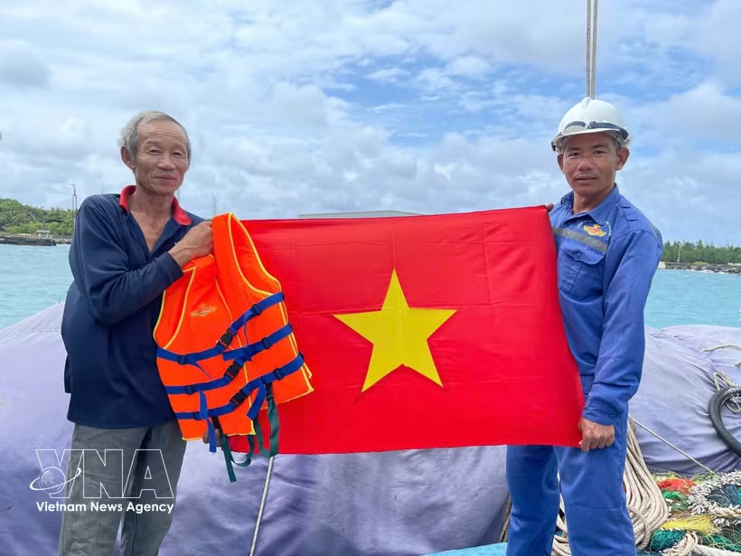 The naval force presents the national flag to a fisherman. (Photo: VNA)