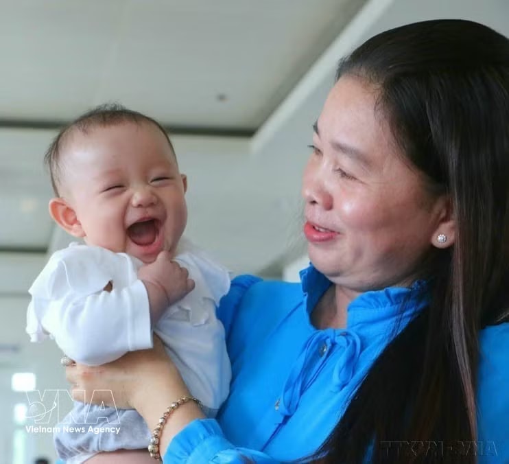 A child accompanies her mother to receive a certificate of merit honouring exemplary families with two daughters, at a ceremony organised in then Hau Giang province on January 5, 2023. (Photo: VNA) 