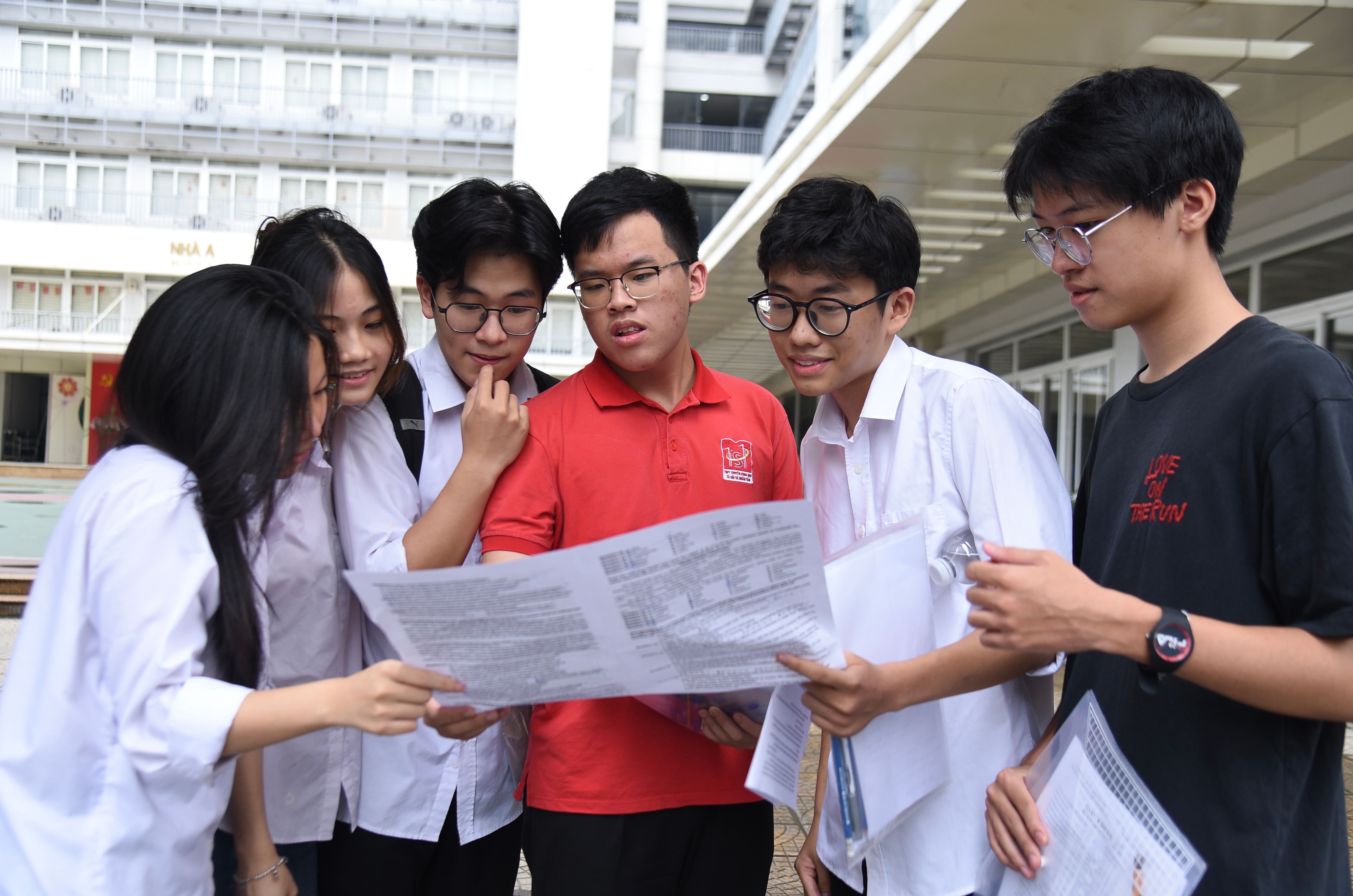 Thí sinh tranh thủ đối chiếu đáp án, chia sẻ cảm nhận ngay sau khi kết thúc bài thi. Ảnh: Xuân Quý