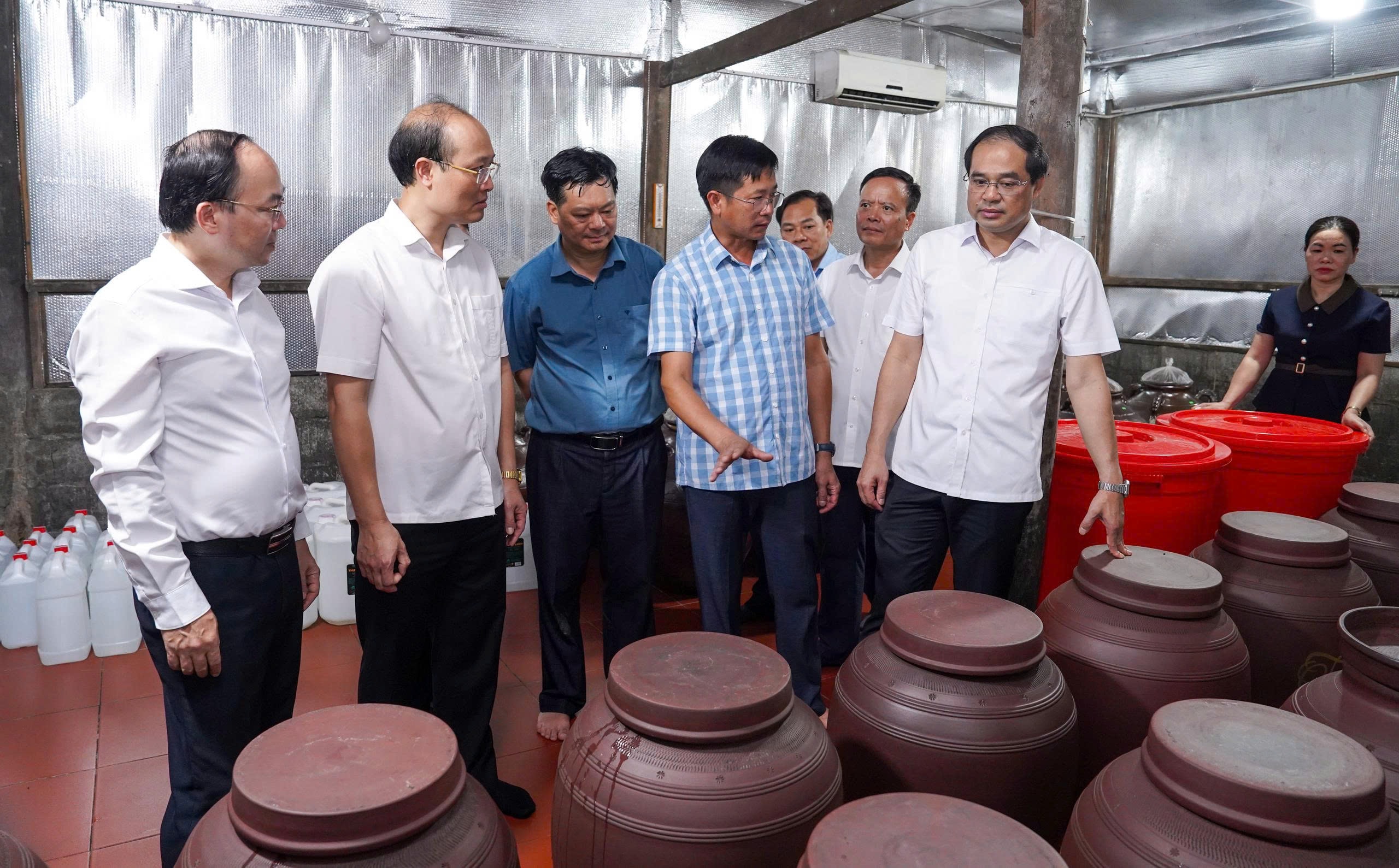 Bí thư Tỉnh ủy Trịnh Xuân Trường và Đoàn công tác khảo sát mô hình sản xuất rượu men lá Thuận Lượm của Hợp tác xã OCOP Quế Thanh. Ảnh: Đồng Văn Thưởng.